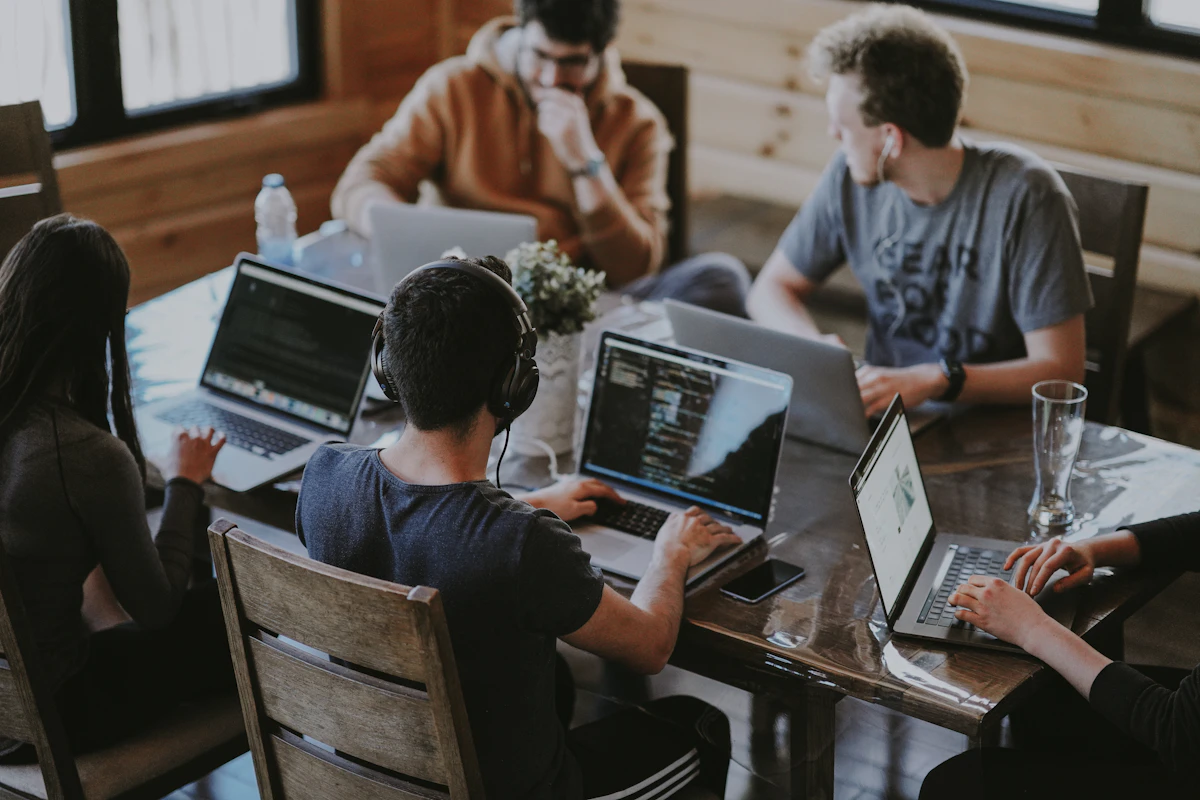 Personas trabajando juntas alrededor de una mesa con sus portátiles